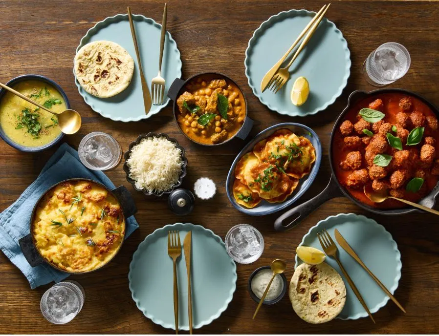 A table spread of Salad Servers Heat and Serve curries, meatballs and sides
