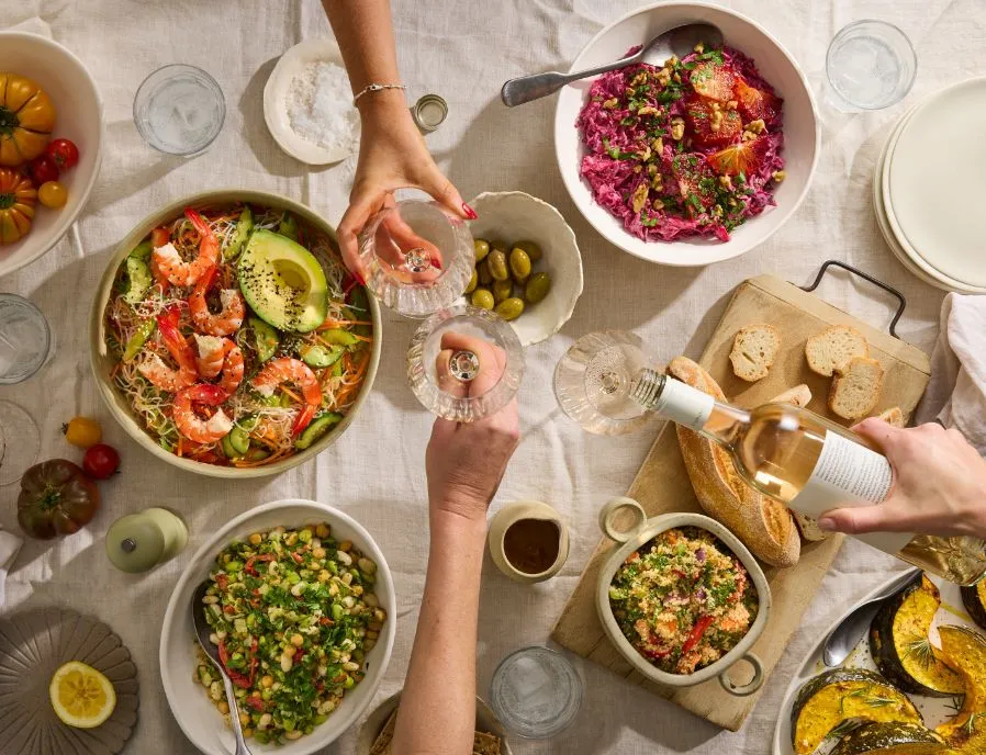 A shared table of Salad Servers salads, sides and wine