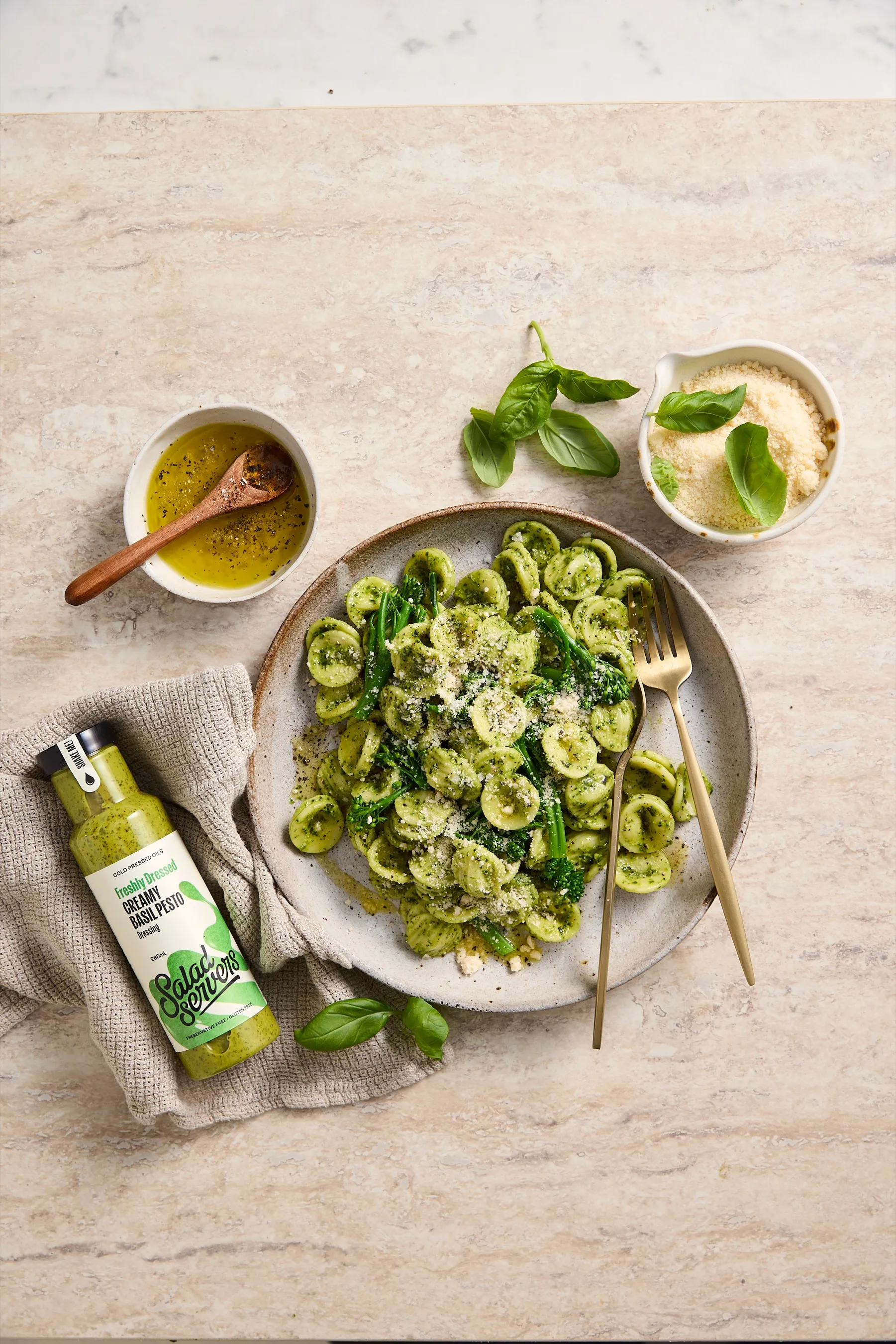 Orecchiette with broccolini and parmesan on a plate, beside a bottle of Salad Servers Creamy Basil Pesto dressing
